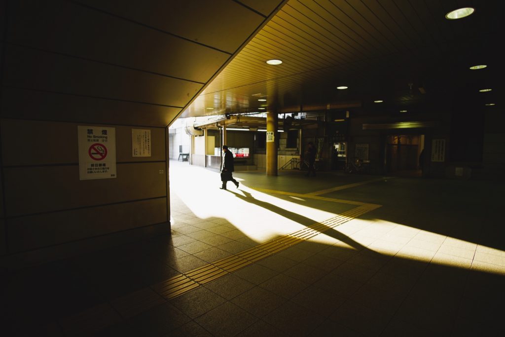 Un salaryman japonais s'empresse de sortir du métro de Tokyo dans la lumière du matin.
