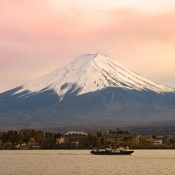 Un vieux bateau de croisière passe sur le lac Kawaguchi devant le Mont Fuji en majesté le ciel embrasé par le couché de soleil