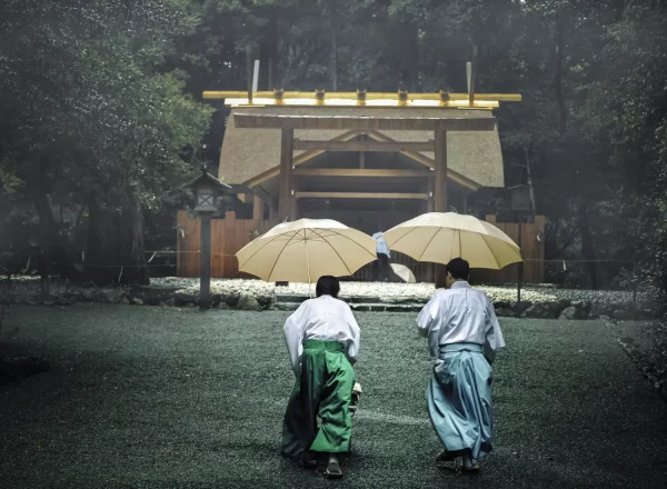 Deux prêtres japonais shinto tenant des parapluies jaunes rentrent vers leur sanctuaire de Ise Jingu au milieu d’une forêt embrumée